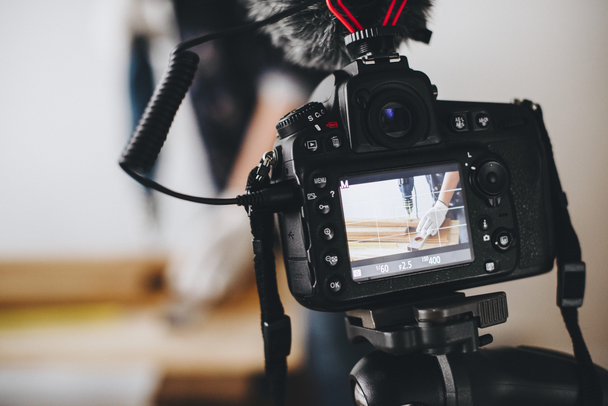 A video camera recording a man drilling a hole into wood