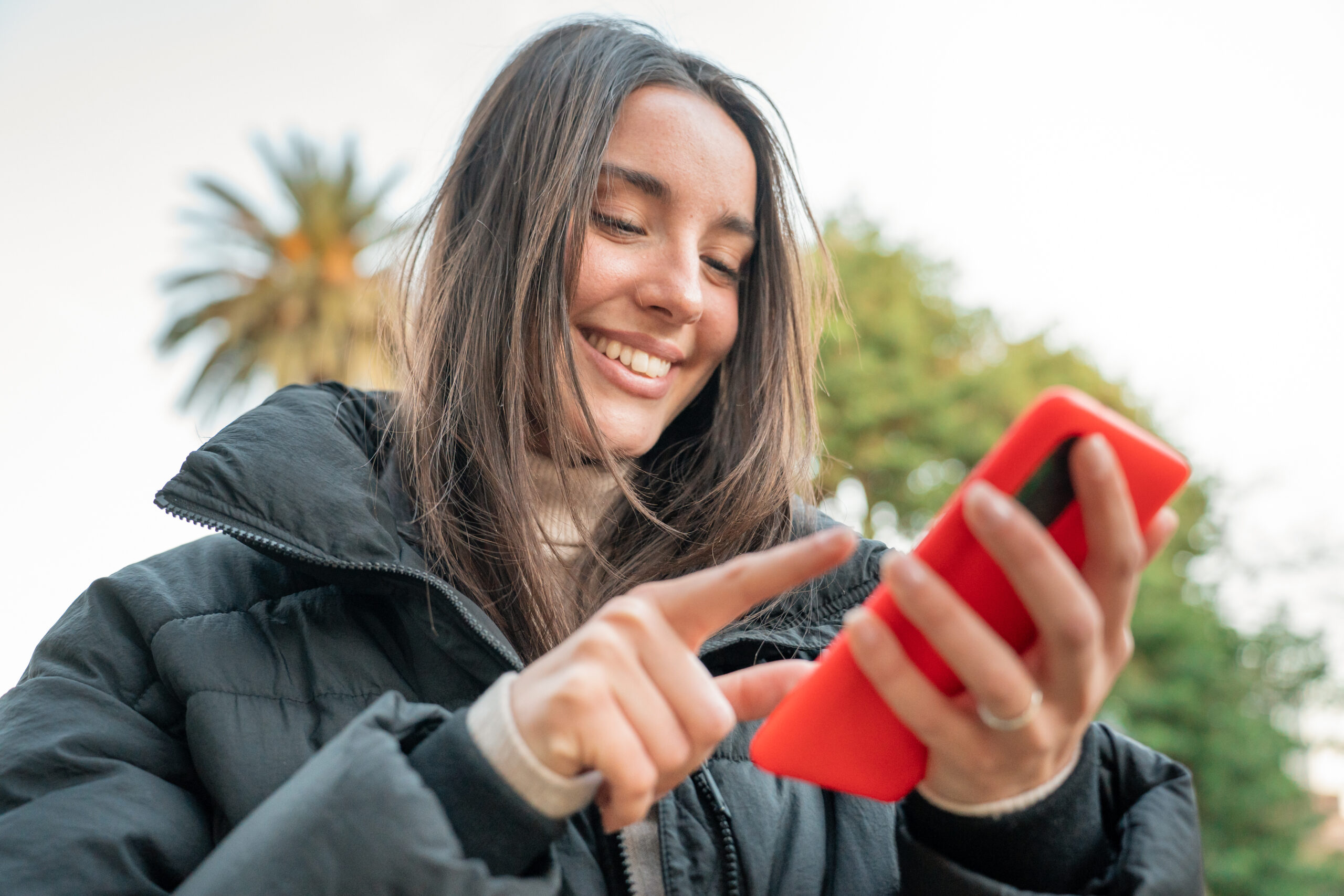 a woman staring happy at her phone while swiping.