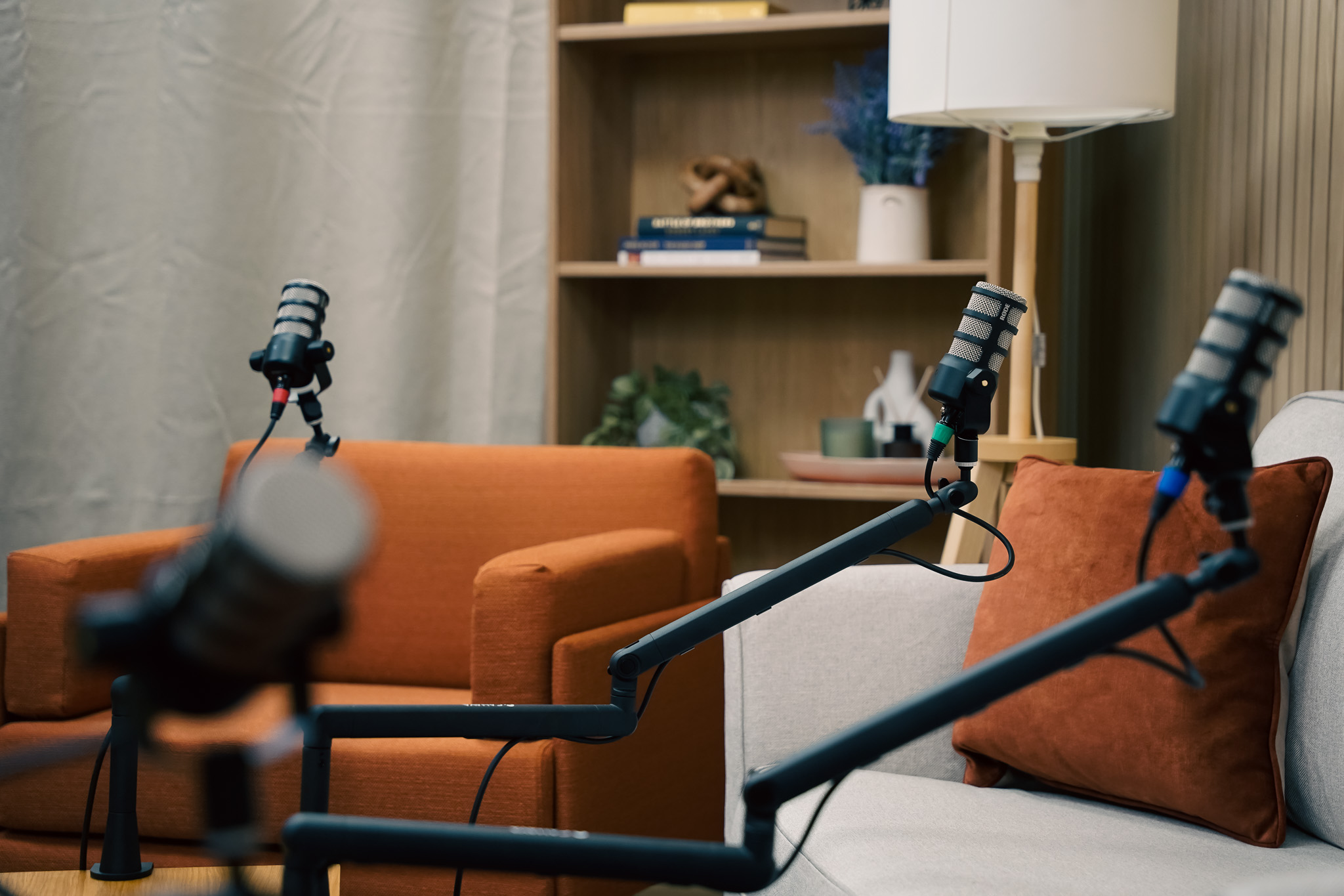 Professional podcast studio setup with broadcast microphones on boom arms, modern seating, and a calm recording space designed for business podcasting and video podcasts.